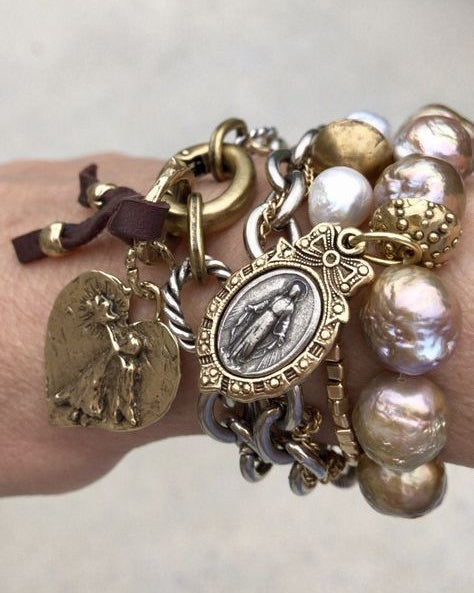 Layered bohemian charm bracelets featuring freshwater pearls, vintage-inspired medallions, and spiritual jewelry details in an elevated eclectic style.