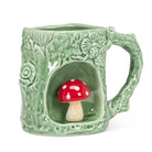 Green ceramic mug shaped like a hollow log with a 3D red and white toadstool tucked inside. 