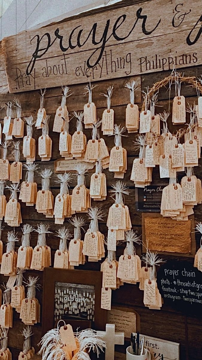 The prayer wall at Crooked Halos, where handwritten prayer tags hang on a wood wall reading "pray about everything."